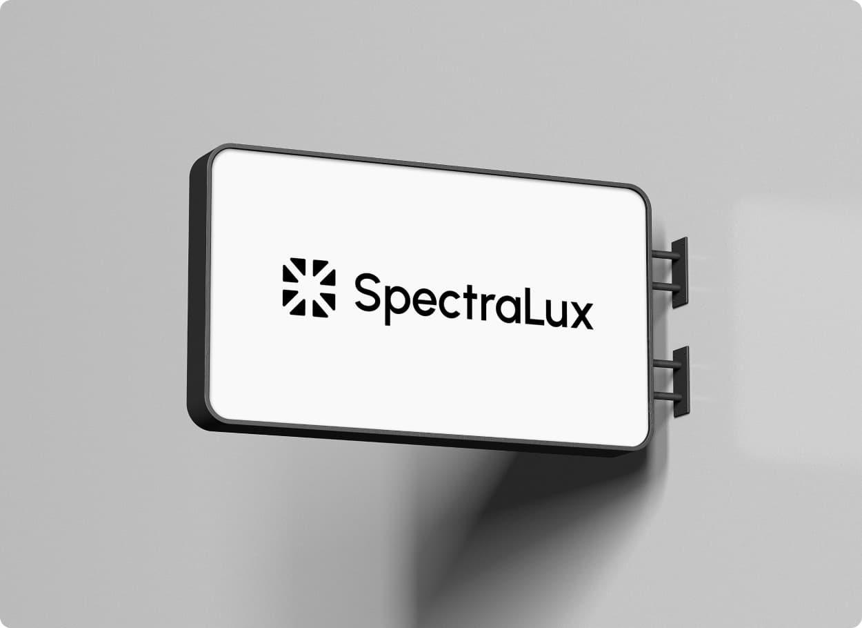 The SpectraLux mark and wordmark in black on a white sign mounted on a grey wall