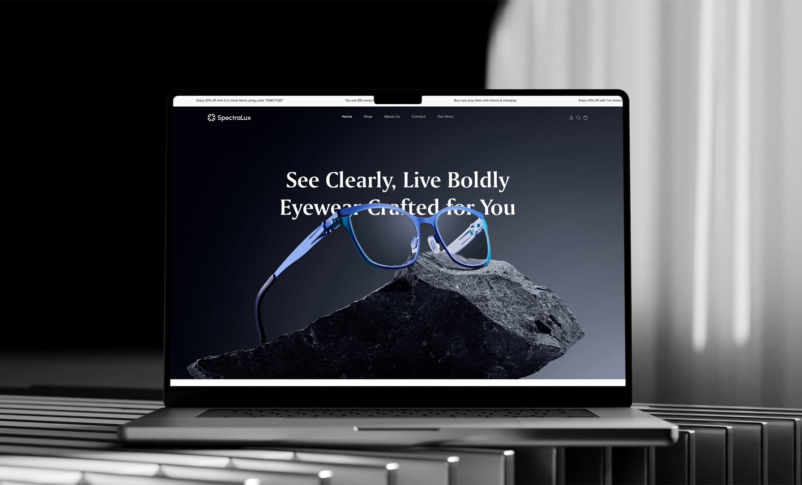 The SpectraLux homepage on a laptop seen from the front, with the menu, the headline See Clearly, Live Boldly and a pair of blue glasses