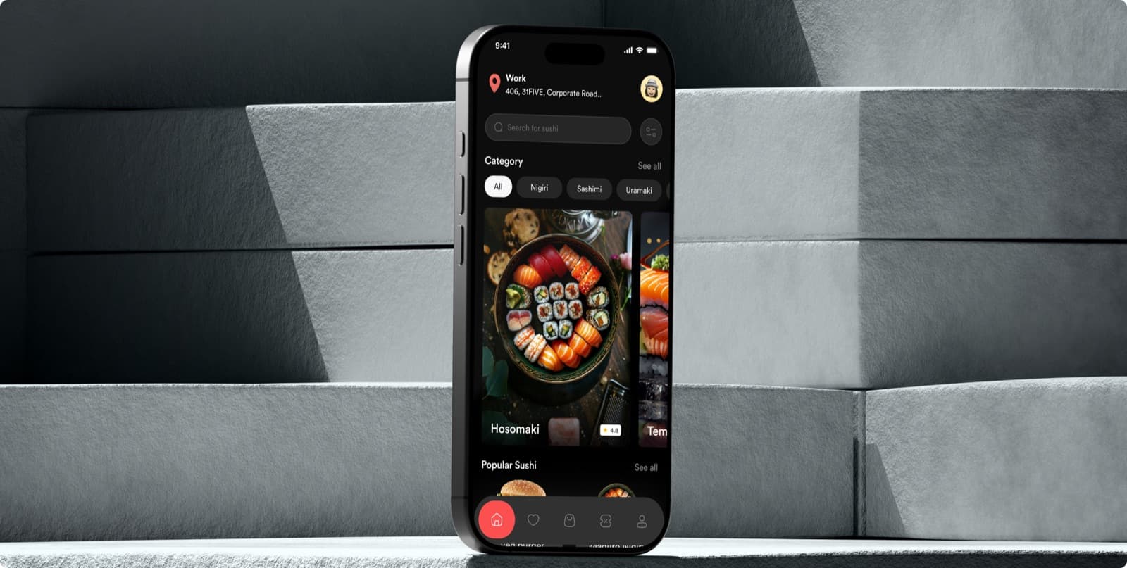 The Zesty app on a phone standing on grey stone steps, showing a dark menu with a search bar, sushi categories and a dish named Hosomaki