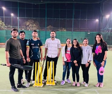 The Redlio Labs team on a floodlit cricket pitch with bats and stumps