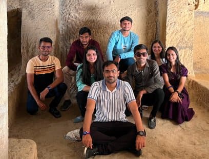 Team members sitting together inside a stone cave on a trip