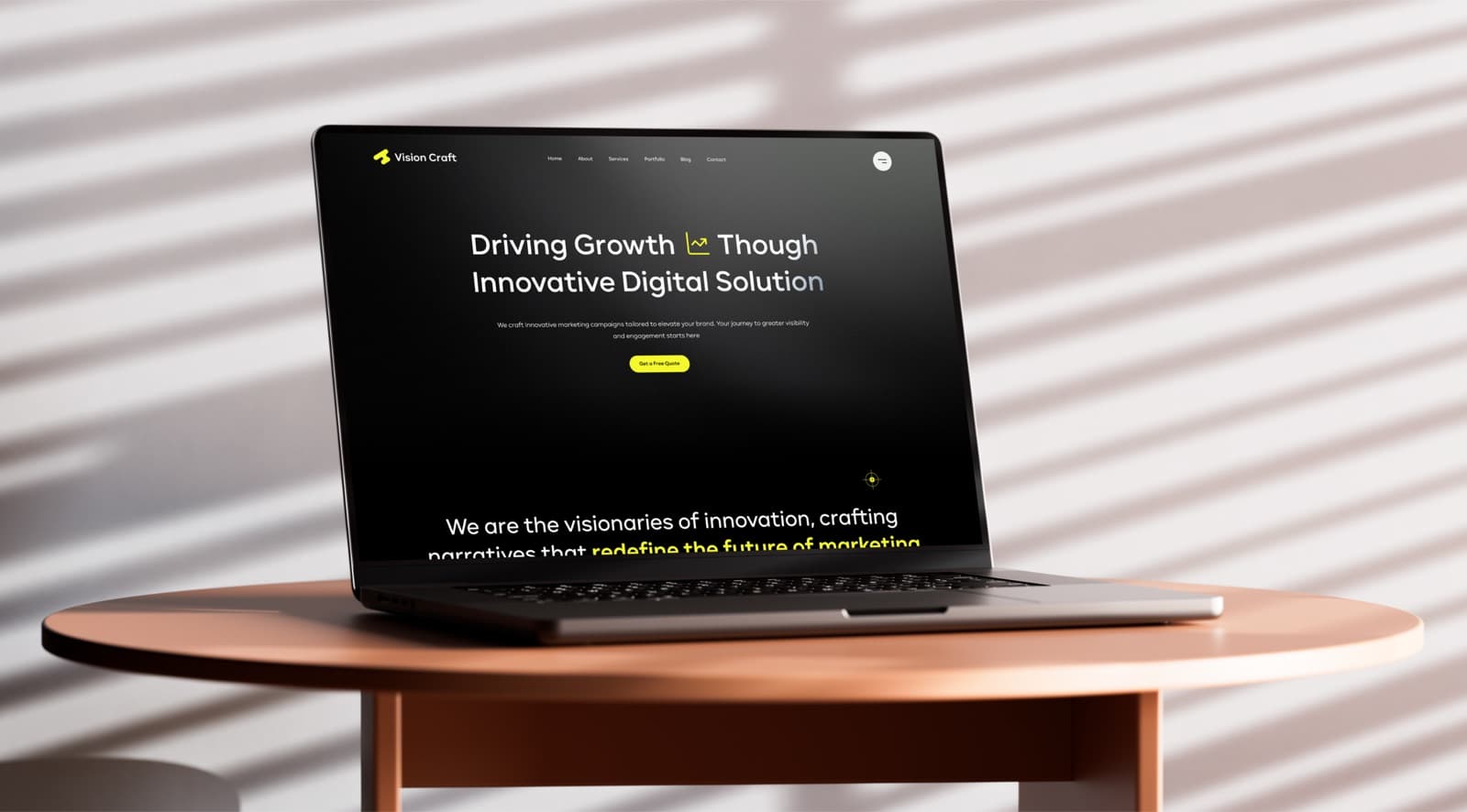 The Vision Craft website on a laptop on a round table, with a headline that begins Driving Growth and a yellow Get a Free Quote button