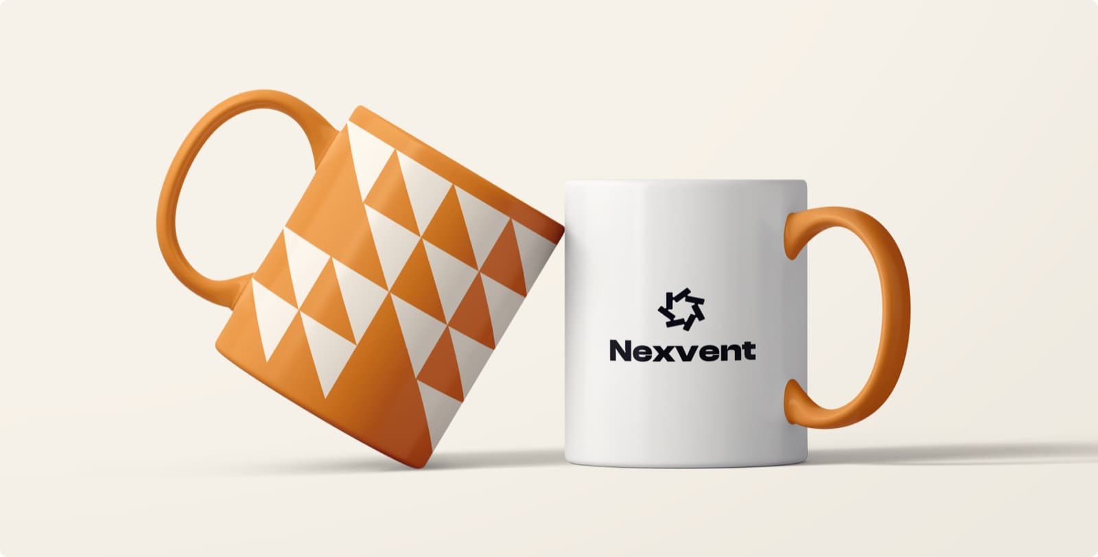 Two mugs with orange handles, one carrying the Nexvent mark and wordmark and one an orange triangle pattern