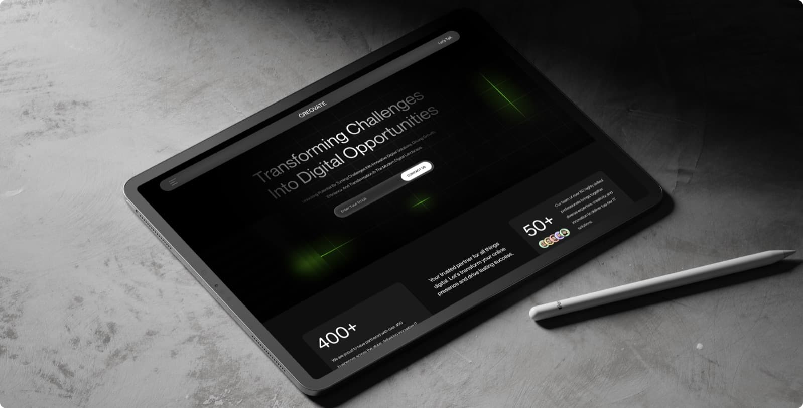 The Creovate homepage on a tablet beside a stylus, showing the headline, the email field and two figures in large type
