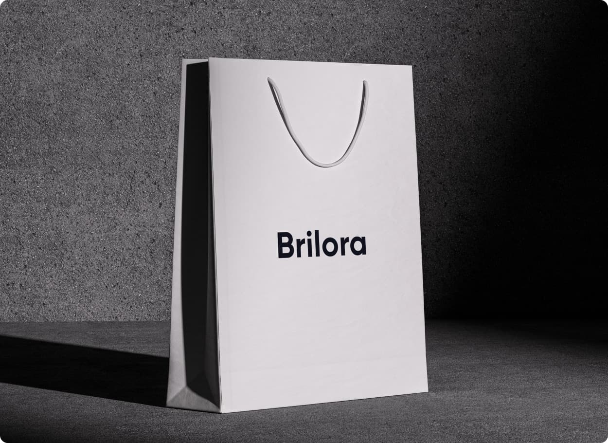A white paper shopping bag carrying the Brilora wordmark