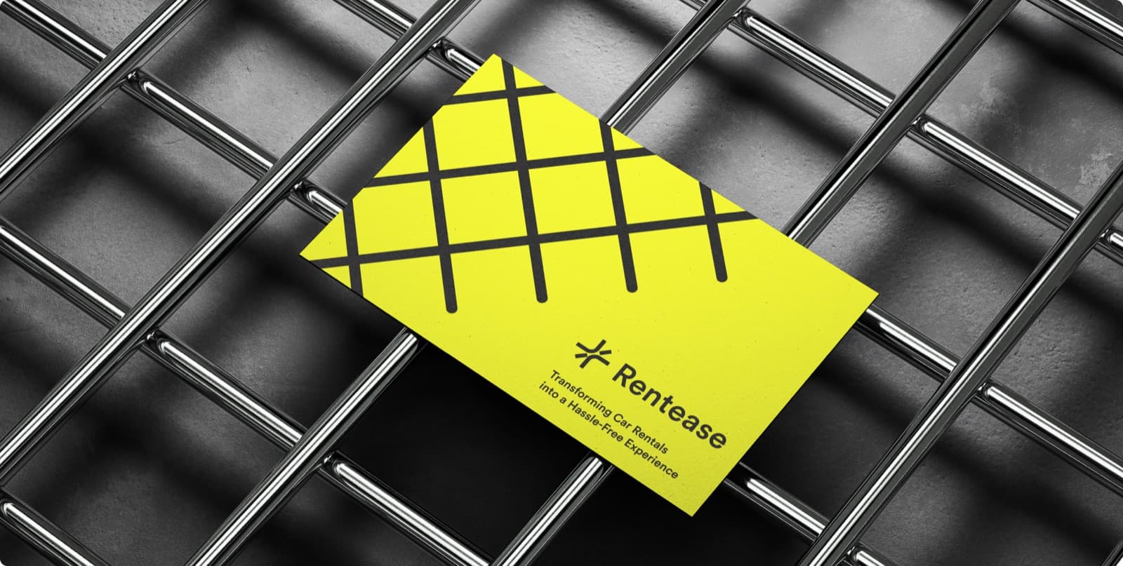A yellow Rentease business card with a black lattice pattern and the line Transforming Car Rentals into a Hassle-Free Experience, lying on a steel grid