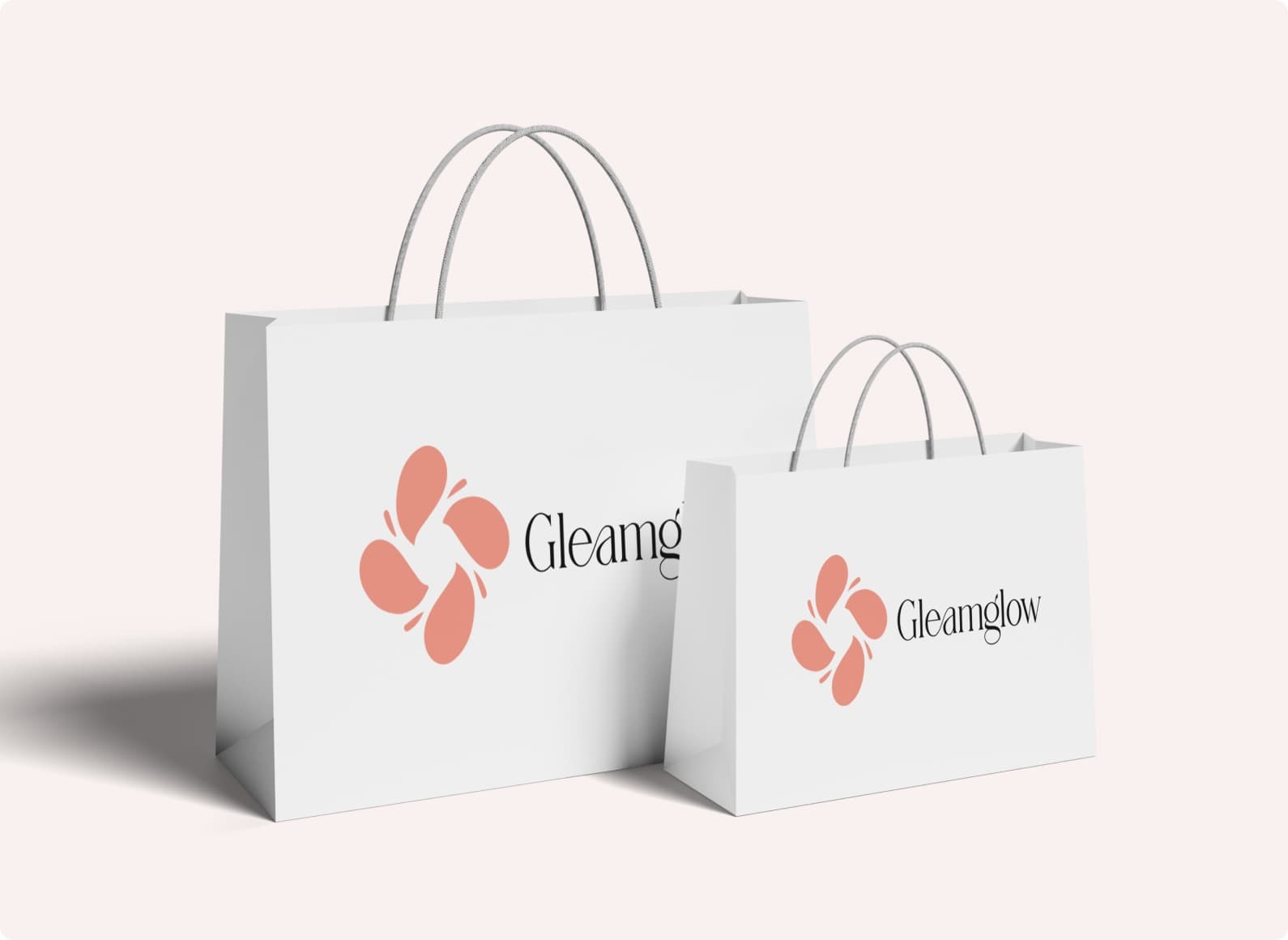 Two white paper shopping bags carrying the Gleamglow mark, a pink four-petal shape, and the name