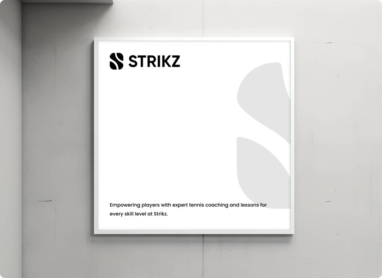 A white Strikz poster in a frame on a concrete wall, with the mark, the wordmark and one line about tennis coaching