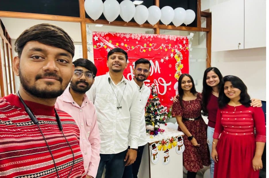 Team members taking a group selfie beside Christmas decorations in the office