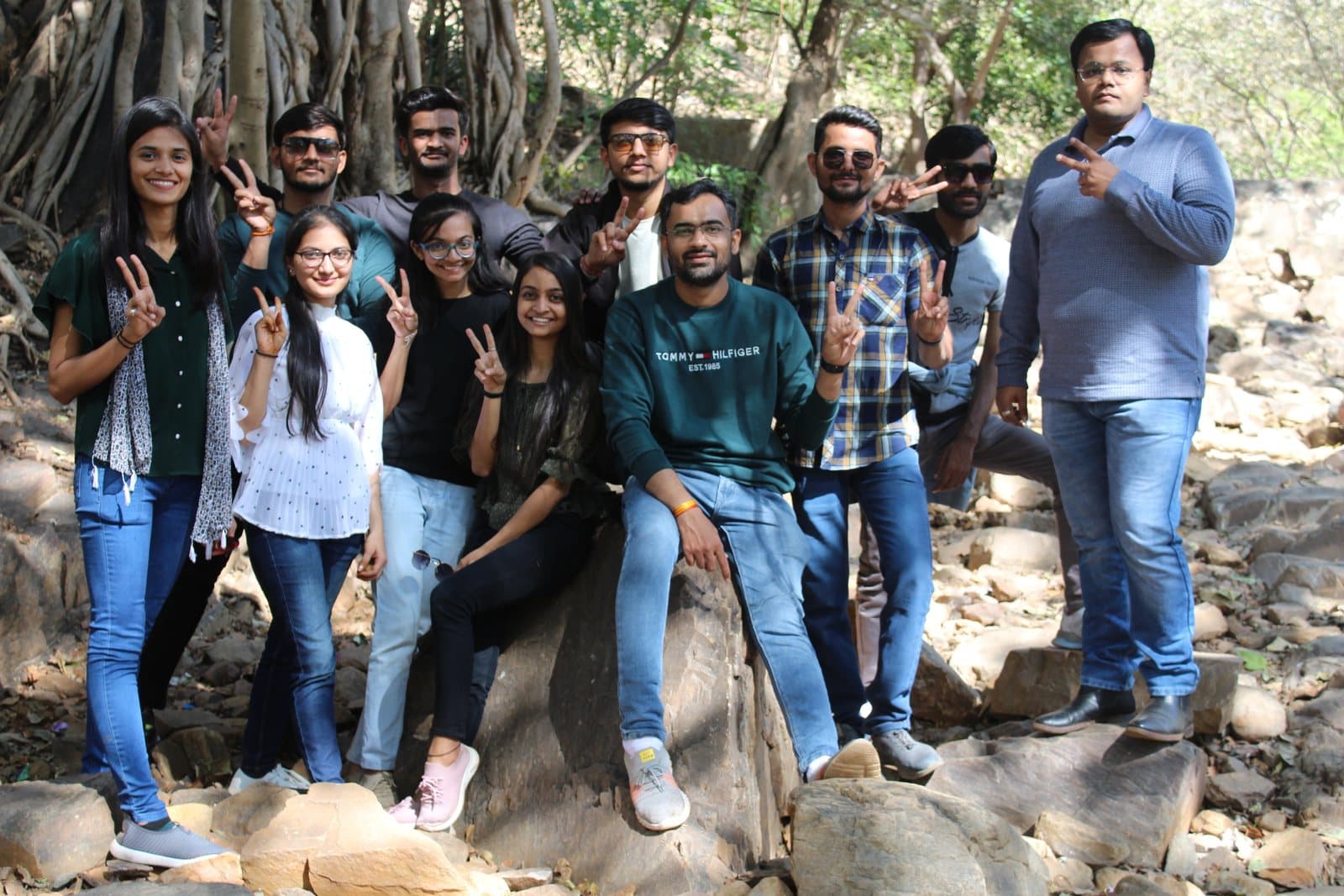 The Redlio Labs team on a day out, standing together on rocks under a banyan tree
